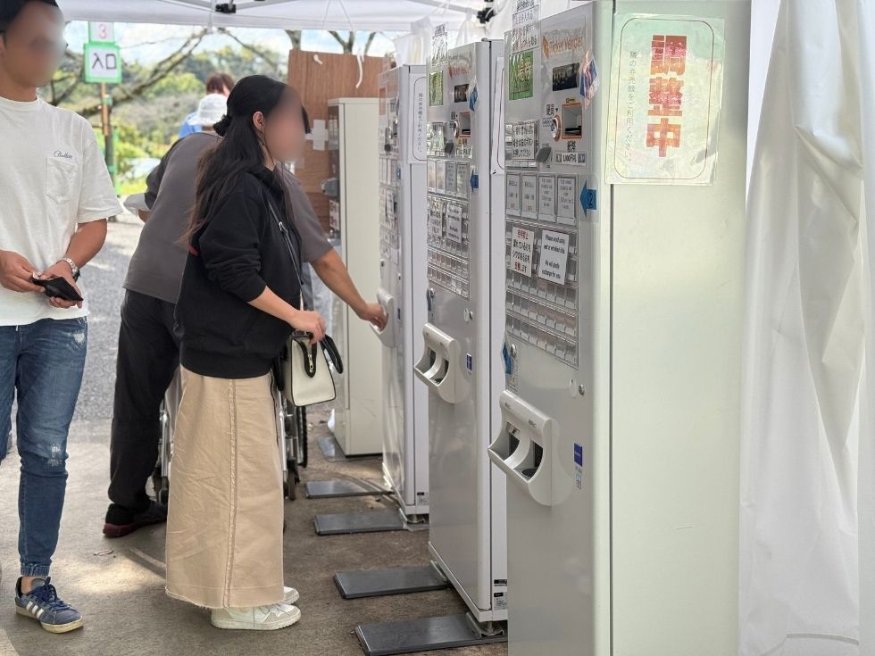 キャラバンテント内に設置されてる券売機で券を買う来場者