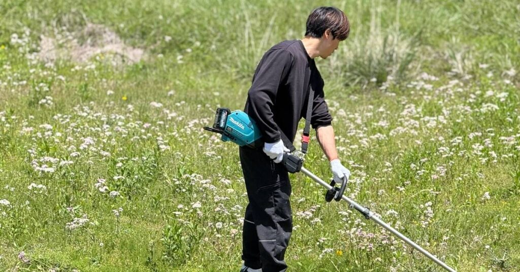 広大な庭でマキタの草刈機を使い草刈をするアトラスのスタッフ甲斐田隼