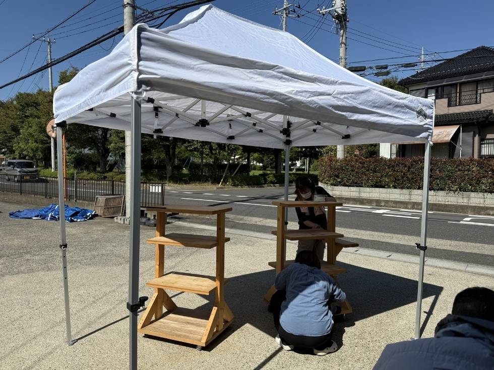 ワンタッチテントを使って屋外の炎天下で作業するアトラスの女性スタッフ