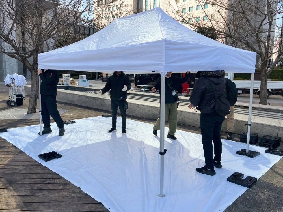 イベント会場の準備でテントを設営するアトラスのスタッフ