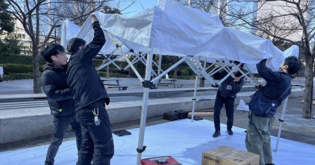 ワンタッチテントを組み立てる主催者のMさんとイベント運営会社のスタッフ