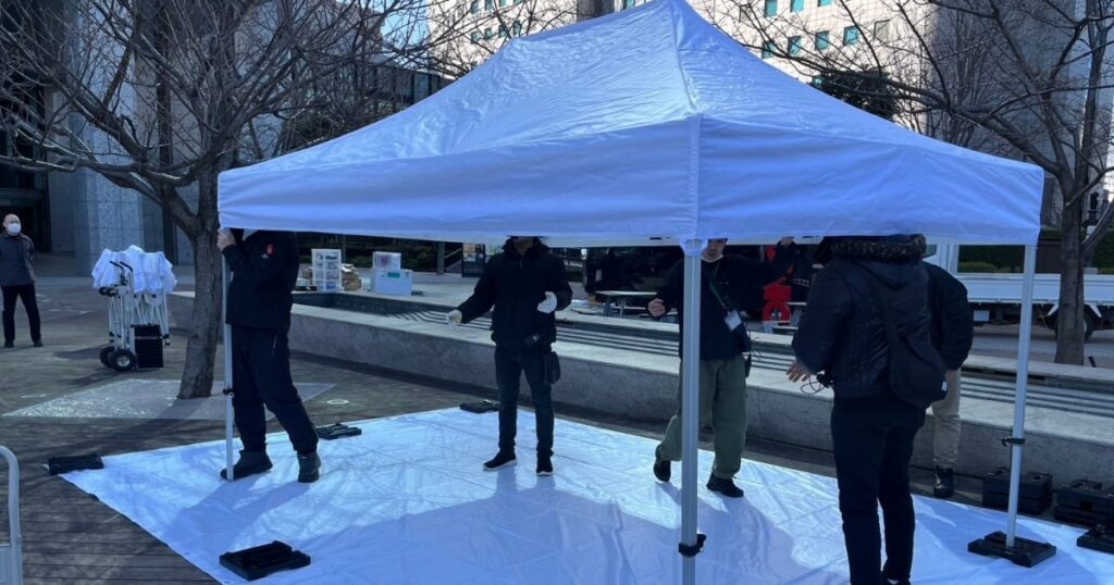 イベント主催者スタッフにテント設営の指導をするアトラスの社長