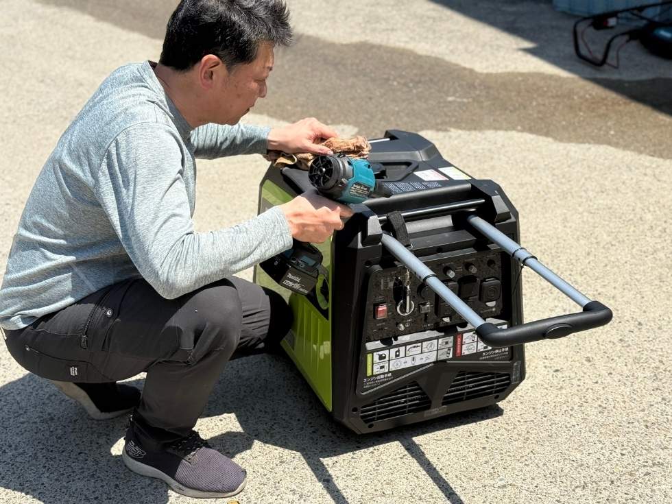 発電機DK7250ieの埃をエアダスターで除去するアトラスのスタッフ亀山くん