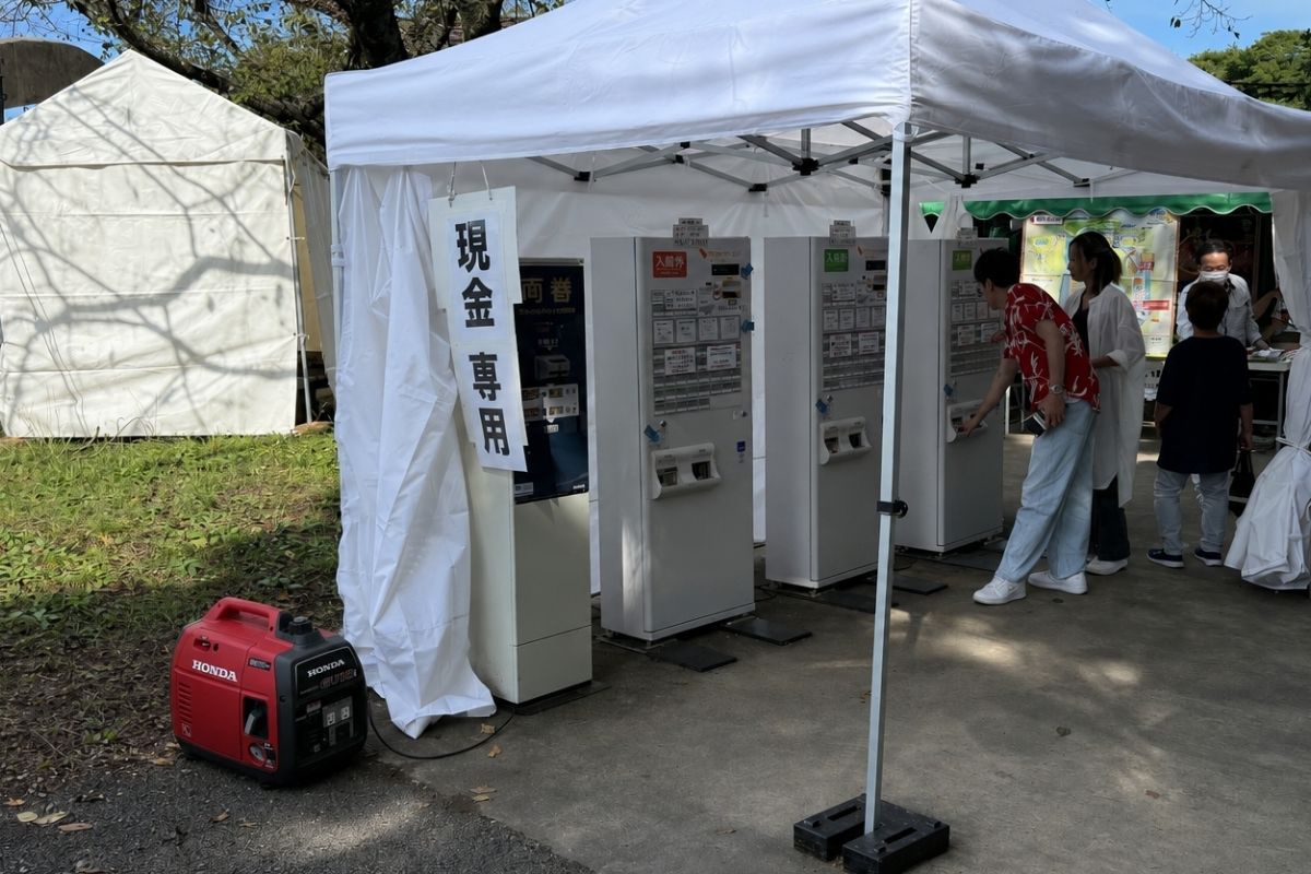 業務用テントの横に発電機を設置して券売機の電源を確保してる様子