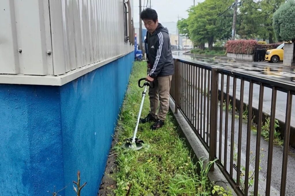 草刈機で倉庫まわりの雑草を刈るアトラスの社長