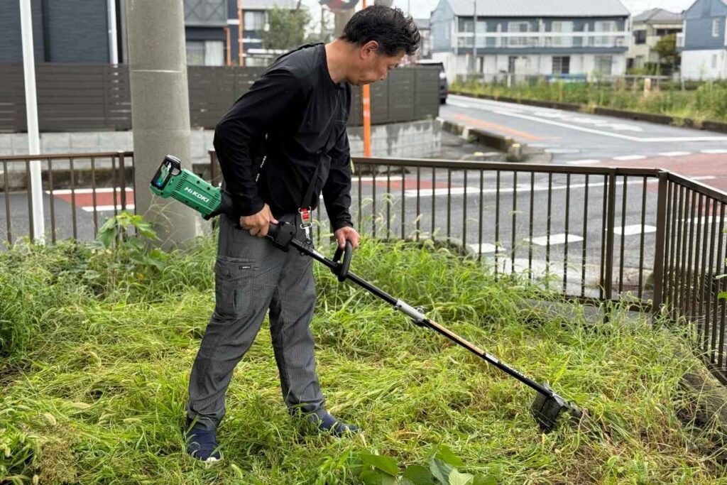 アトラス倉庫敷地内でHiKOKI CG36DC草刈機を使うスタッフ