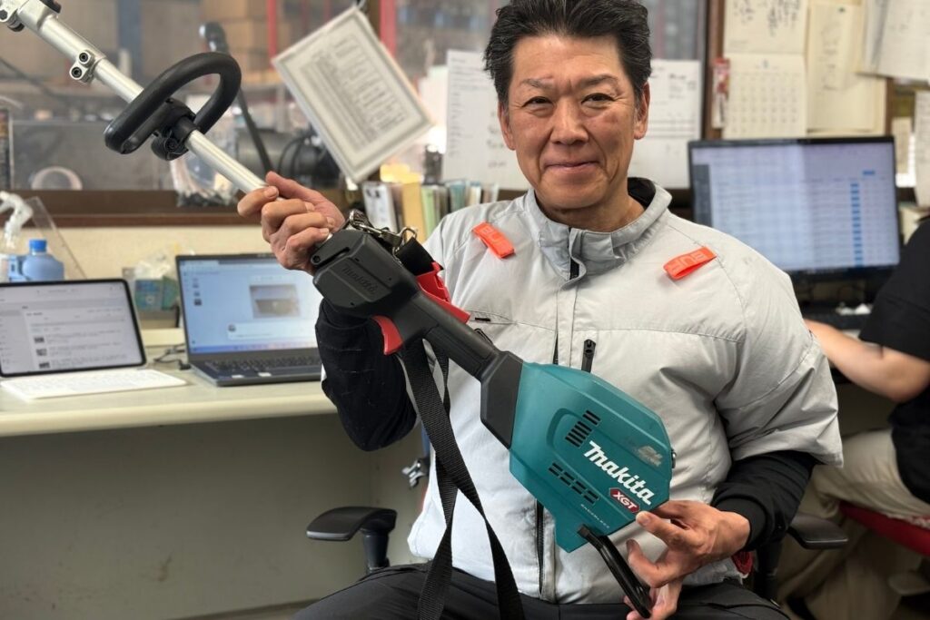 マキタの充電式草刈機を抱えて紹介するアトラスのスタッフ
